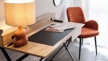 A modern room with a wooden desk, a lamp, a chair, and a remote control.