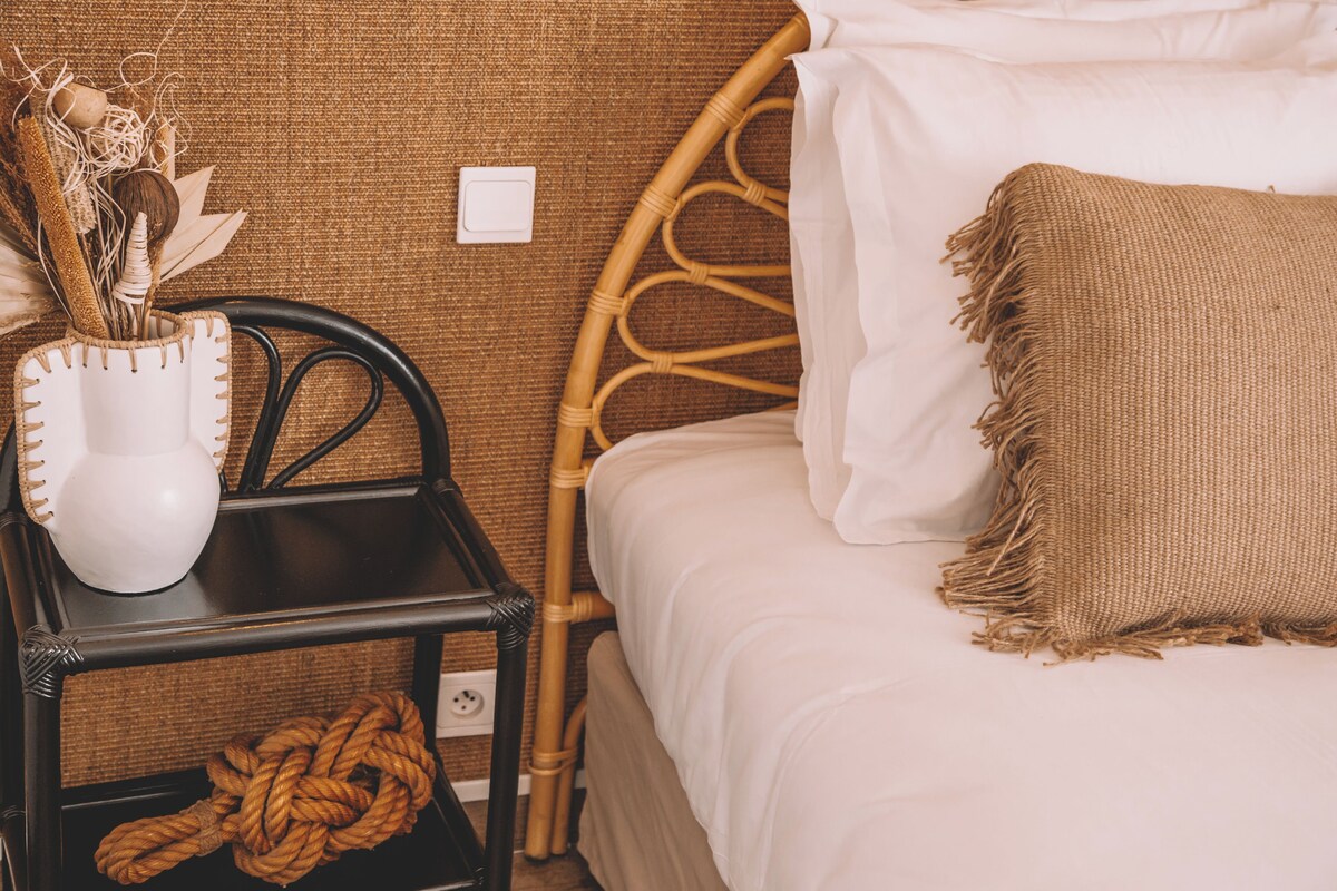 Un lit bien fait, avec un oreiller blanc et un plaid à motifs.