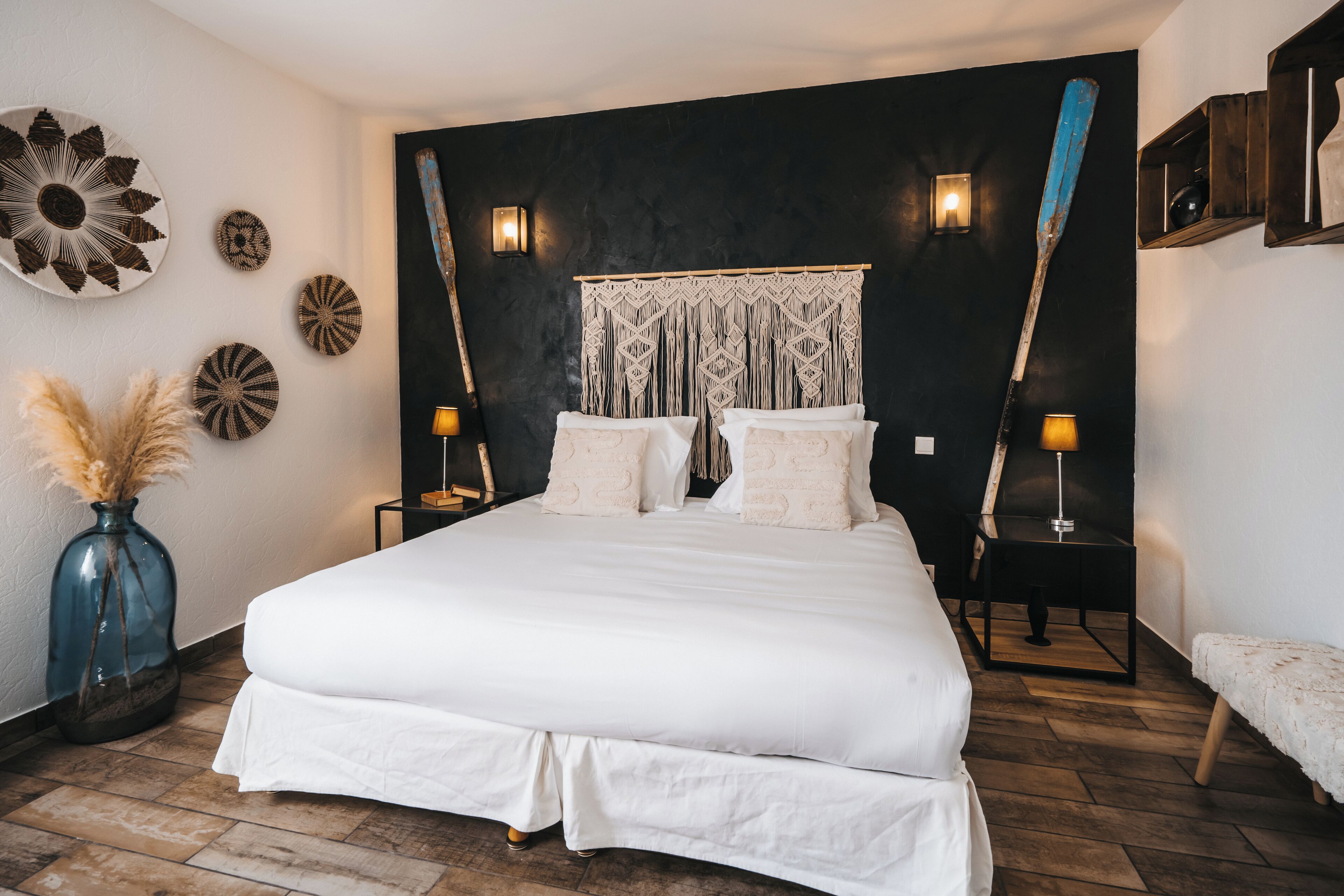 Ein Schlafzimmer mit einem großen Bett, zwei Nachttischen, einer Wanddekoration aus Makramee und Wandlampen.