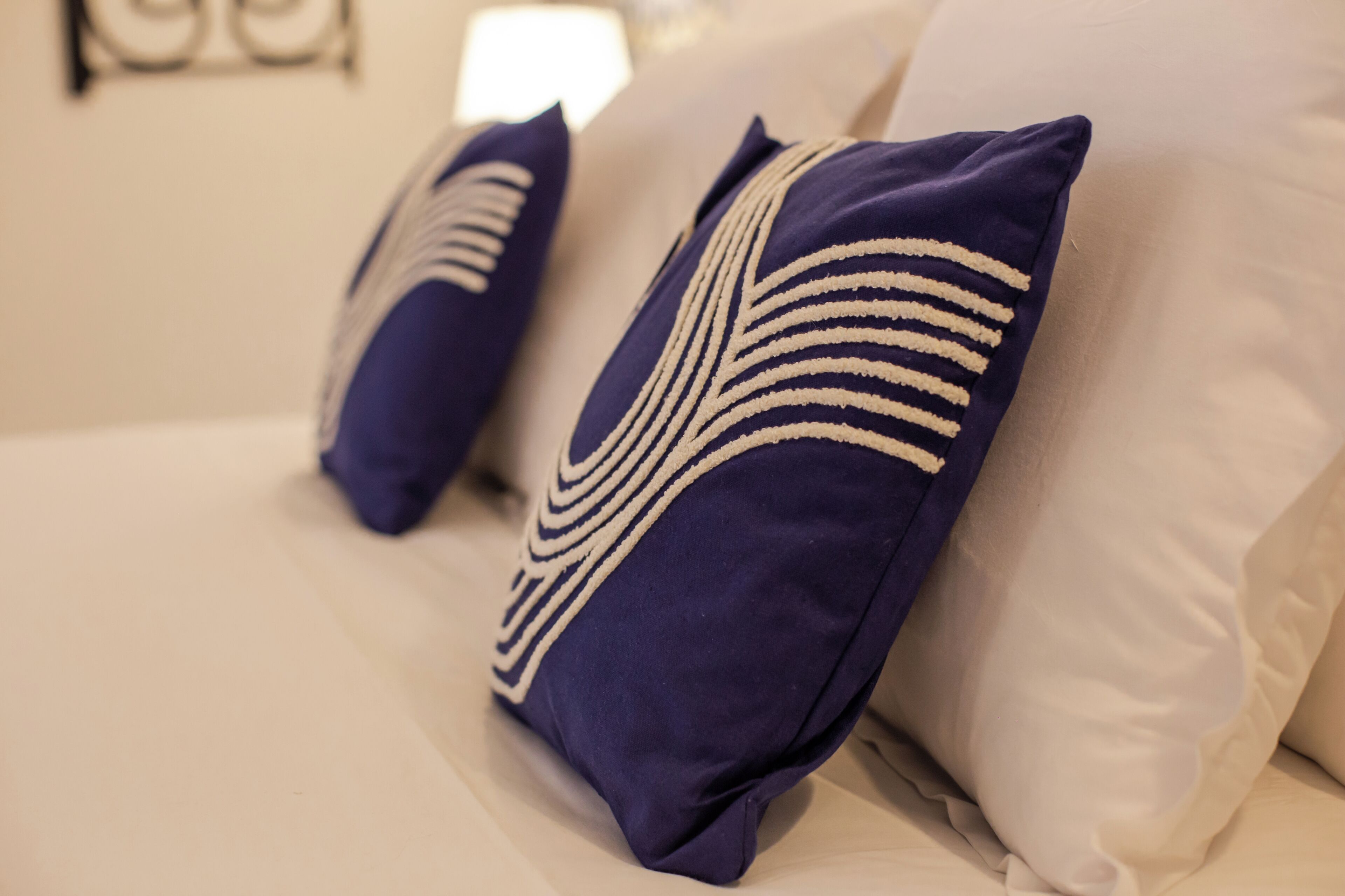 Una cama con dos almohadas, una con estampado a rayas y la otra lisa.