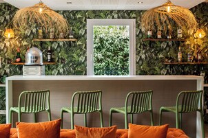 Uma área de bar com cadeiras verdes, um balcão branco e uma janela com vista para o verde.
