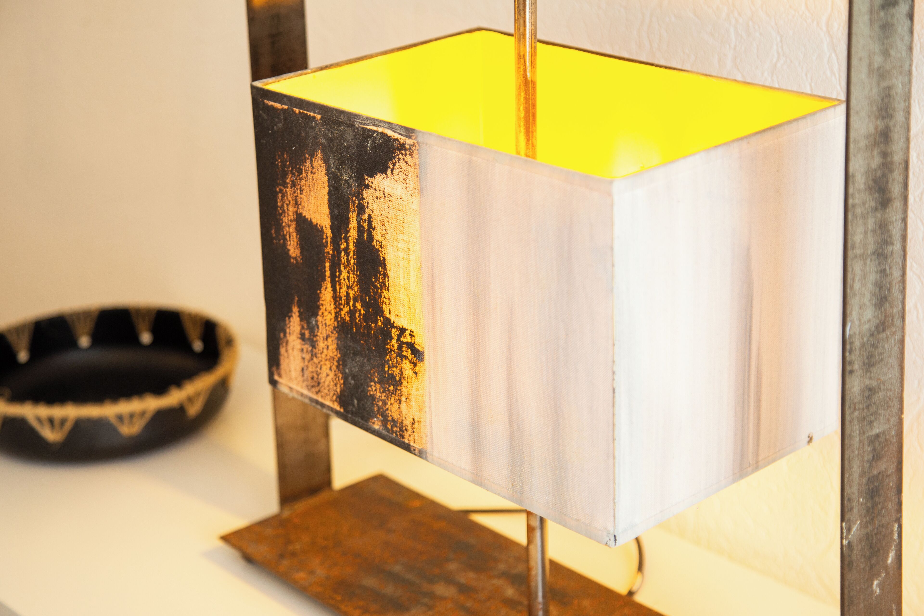 Una lámpara con base de metal desgastada y un interior amarillo brillante.