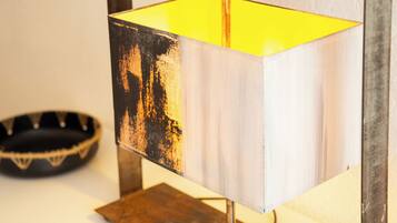 A lamp with a worn, distressed metal base and a bright yellow interior.