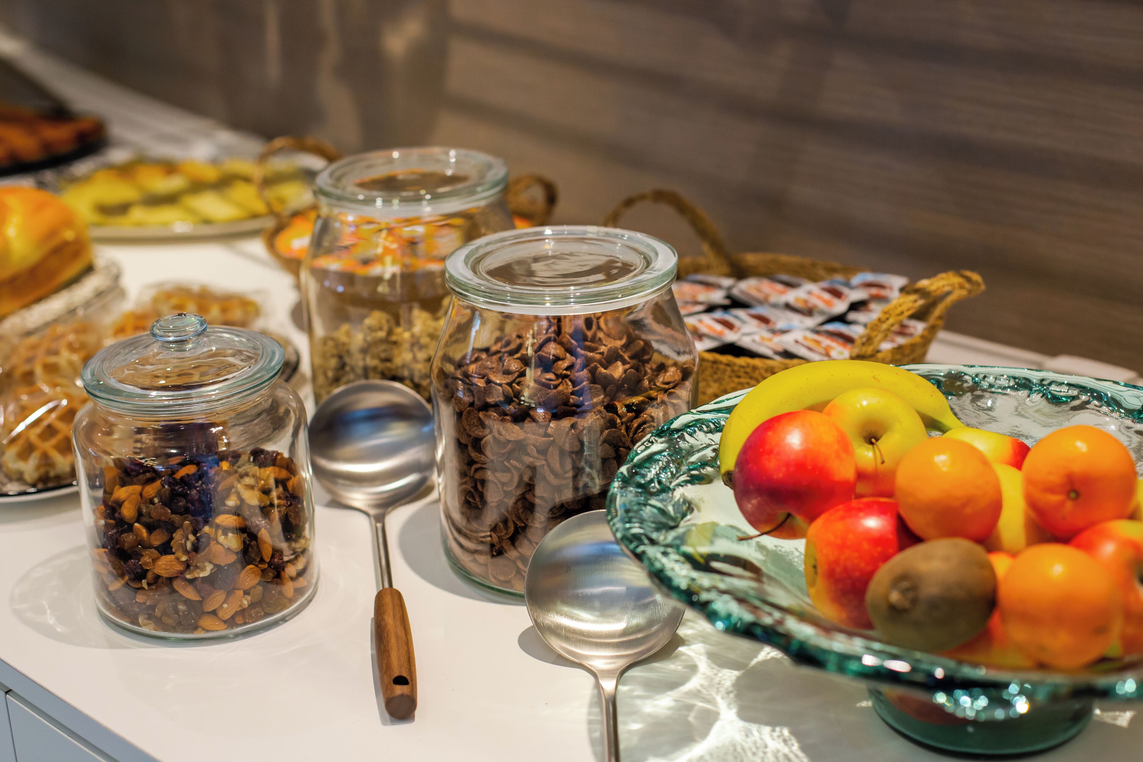 Une table de buffet proposant une variété d’aliments, notamment des fruits, des noix et des pâtisseries.