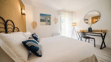 Un dormitorio ordenado con una cama grande, un escritorio y una silla.