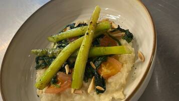 Un tazón de arroz con vegetales y nueces sobre una superficie metálica.