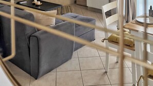 A modern living room with a grey sofa, a fireplace, and a dining area with a table and chairs.