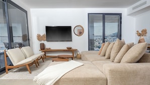 Una sala moderna con un sofá modular, una mesa de centro de madera y un televisor de pantalla plana montado en la pared.