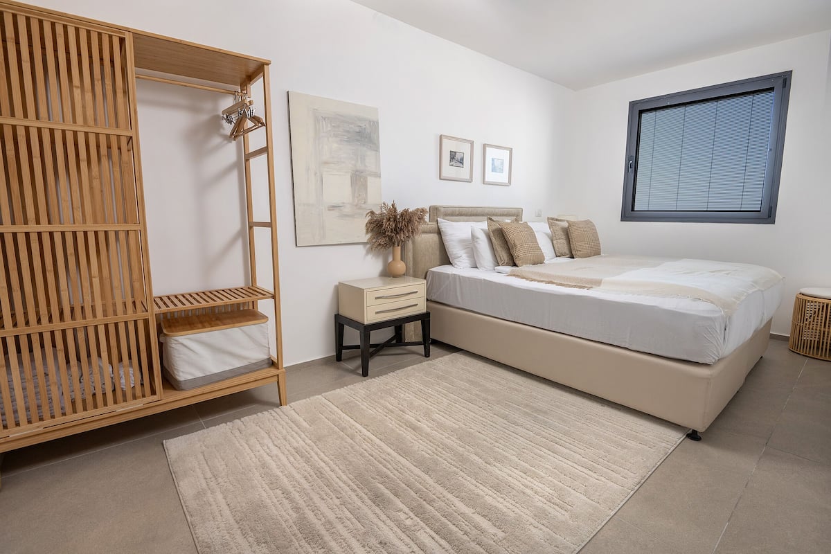 Un dormitorio con cama, mesitas de noche, un armario y una ventana.