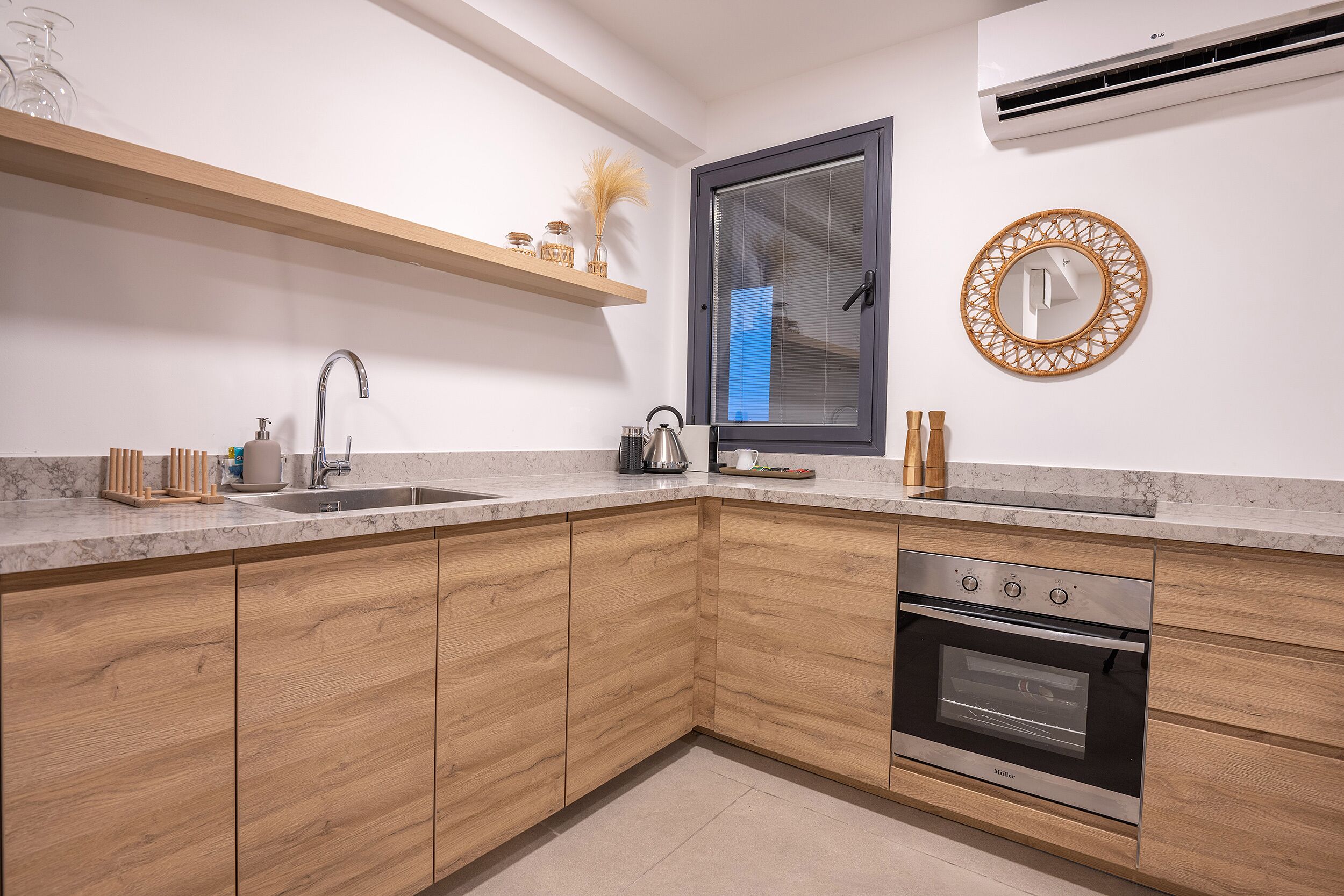 A modern kitchen with wooden cabinets, a built-in oven, a sink, and a window with blinds.