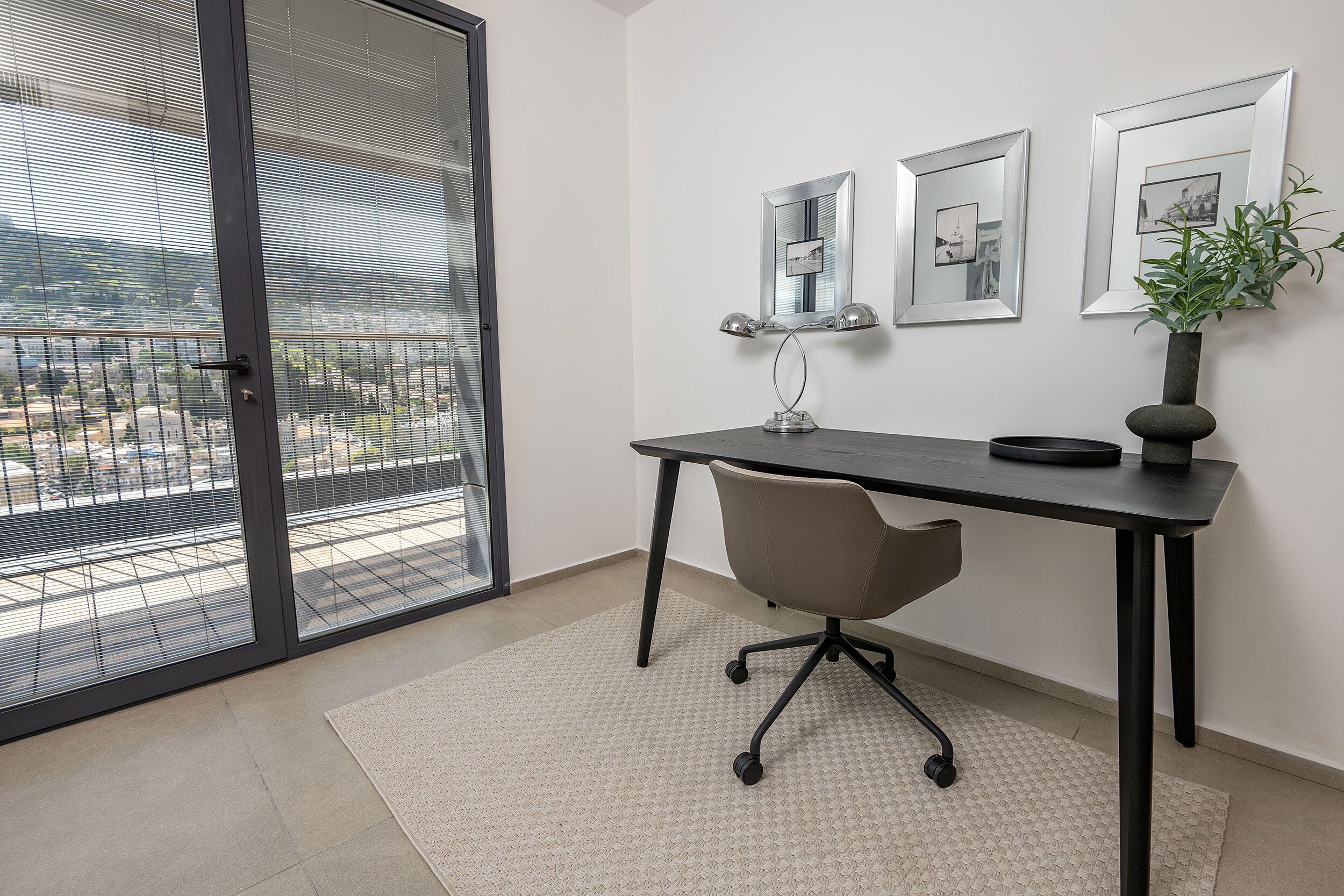 A modern office space with a desk, chair, and large window with blinds.