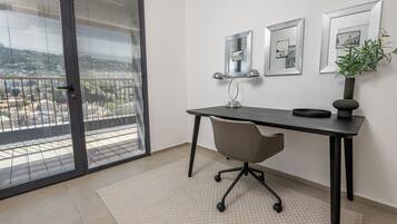A modern office space with a desk, chair, and large window with blinds.
