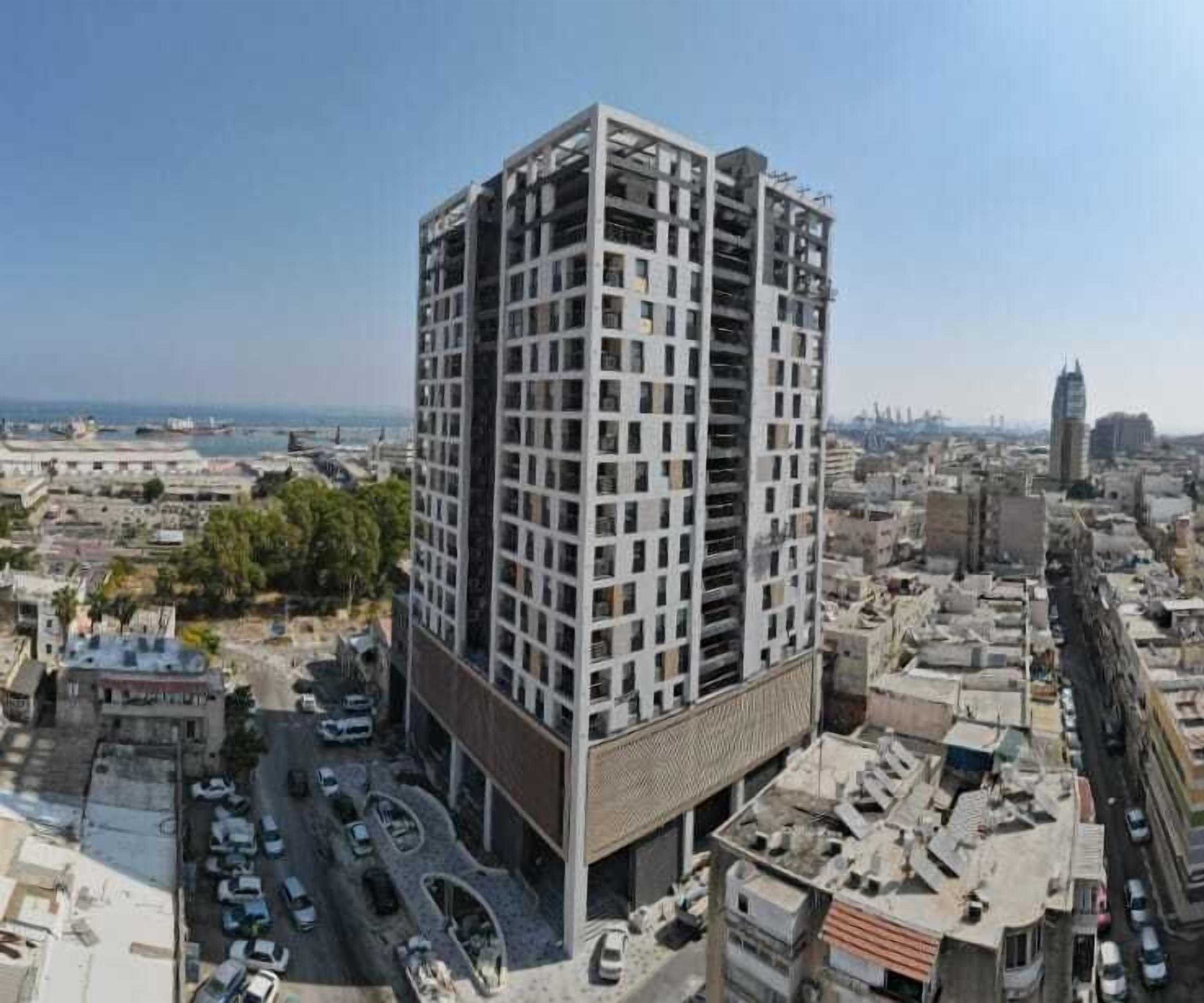 Un edificio de gran altura con diseño moderno, que cuenta con varios balcones y un patio central.
