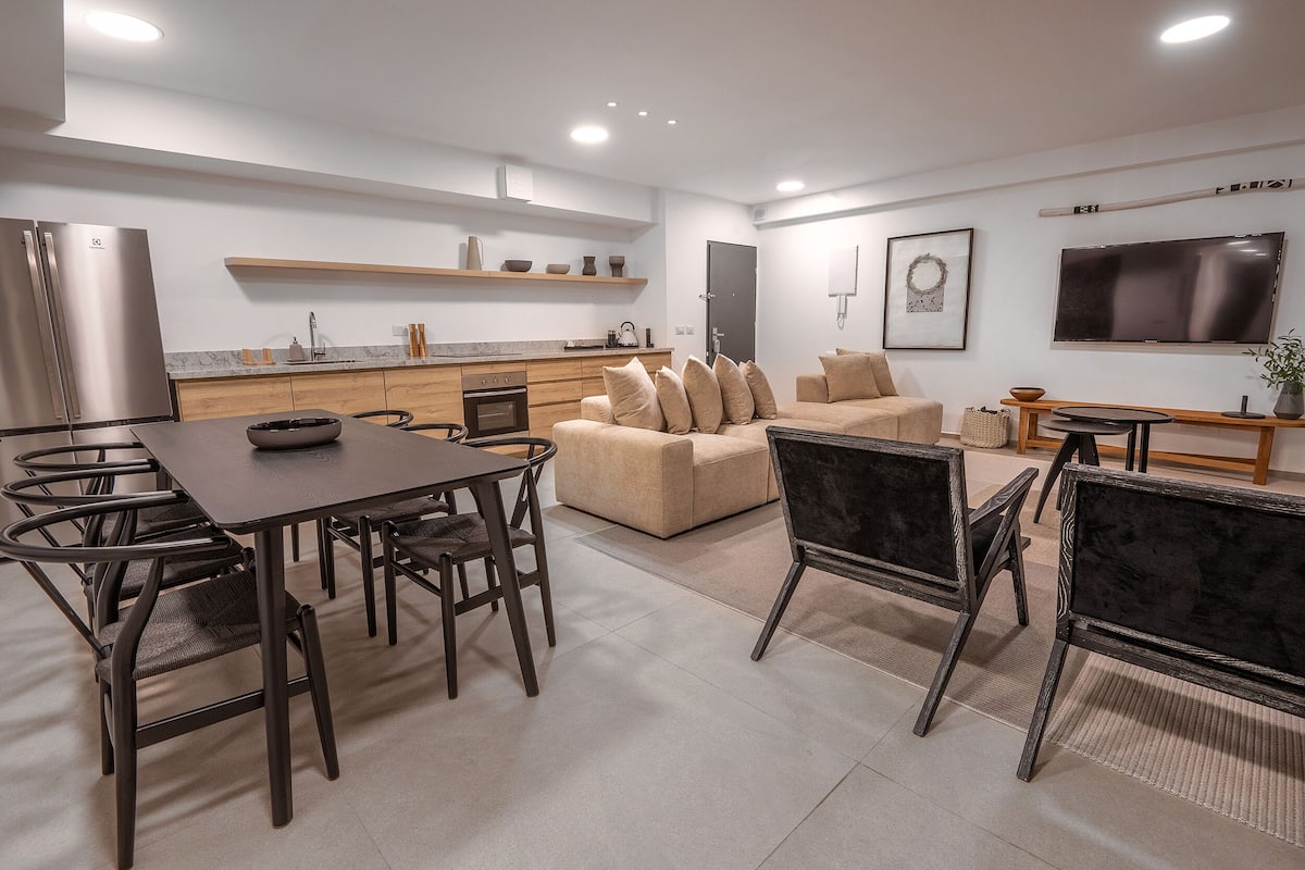 Una cocina moderna con comedor, sofá y televisor.