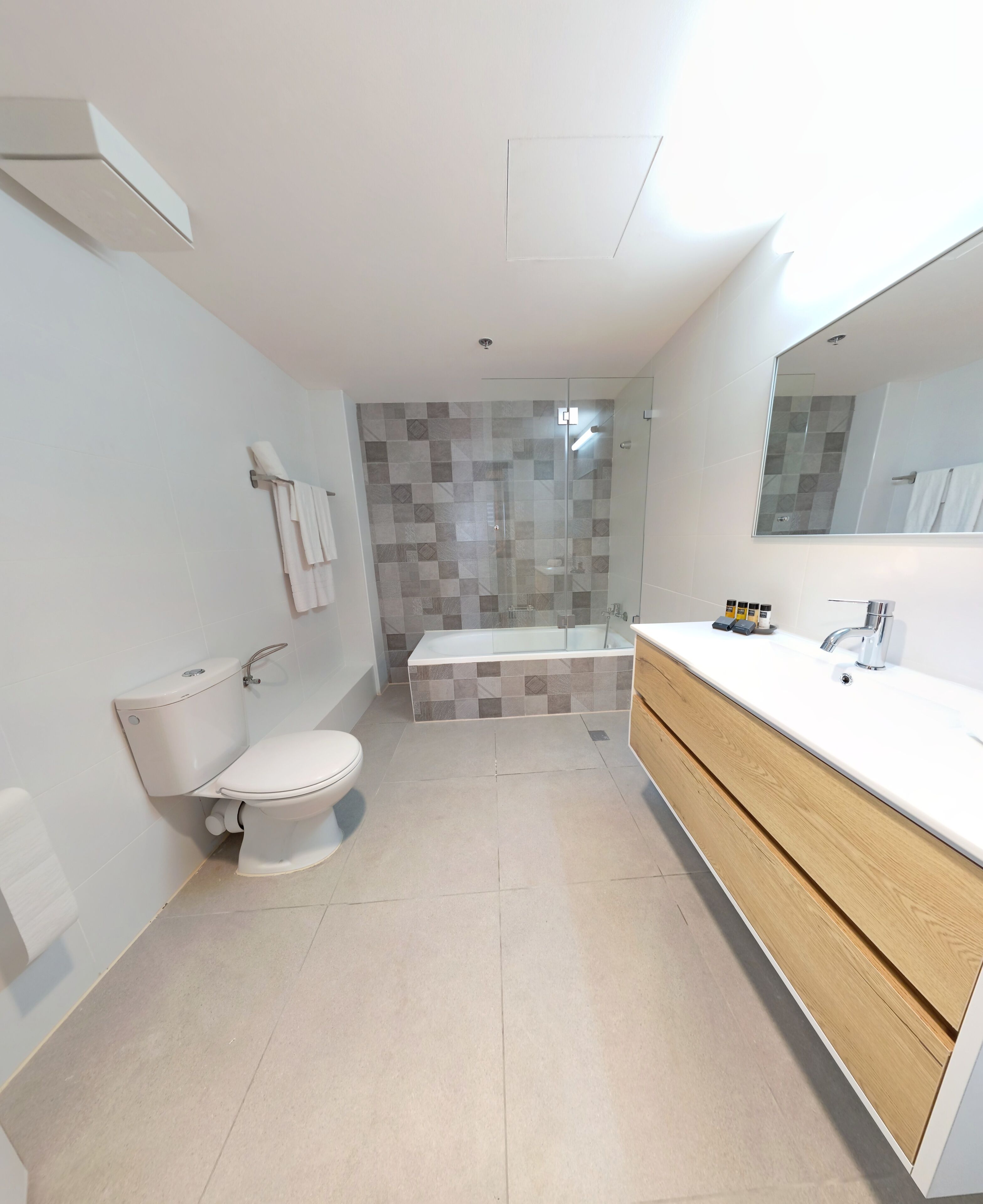 A modern bathroom with a toilet, shower, and vanity.
