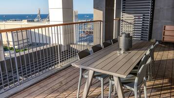 Un balcón con vista al mar, una mesa con sillas y una barandilla de metal.