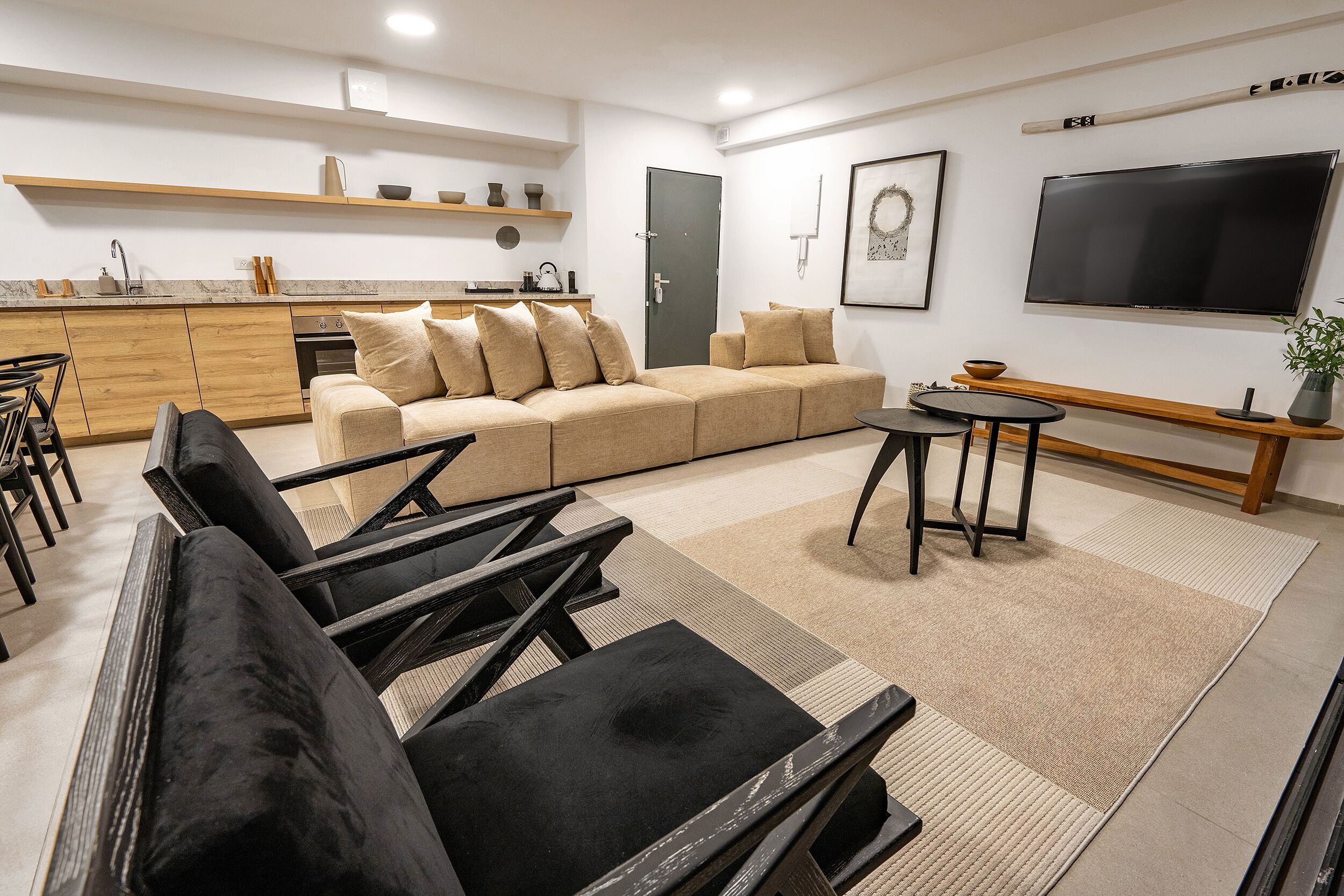 A modern living room with a sofa, black chairs, a coffee table, and a TV.