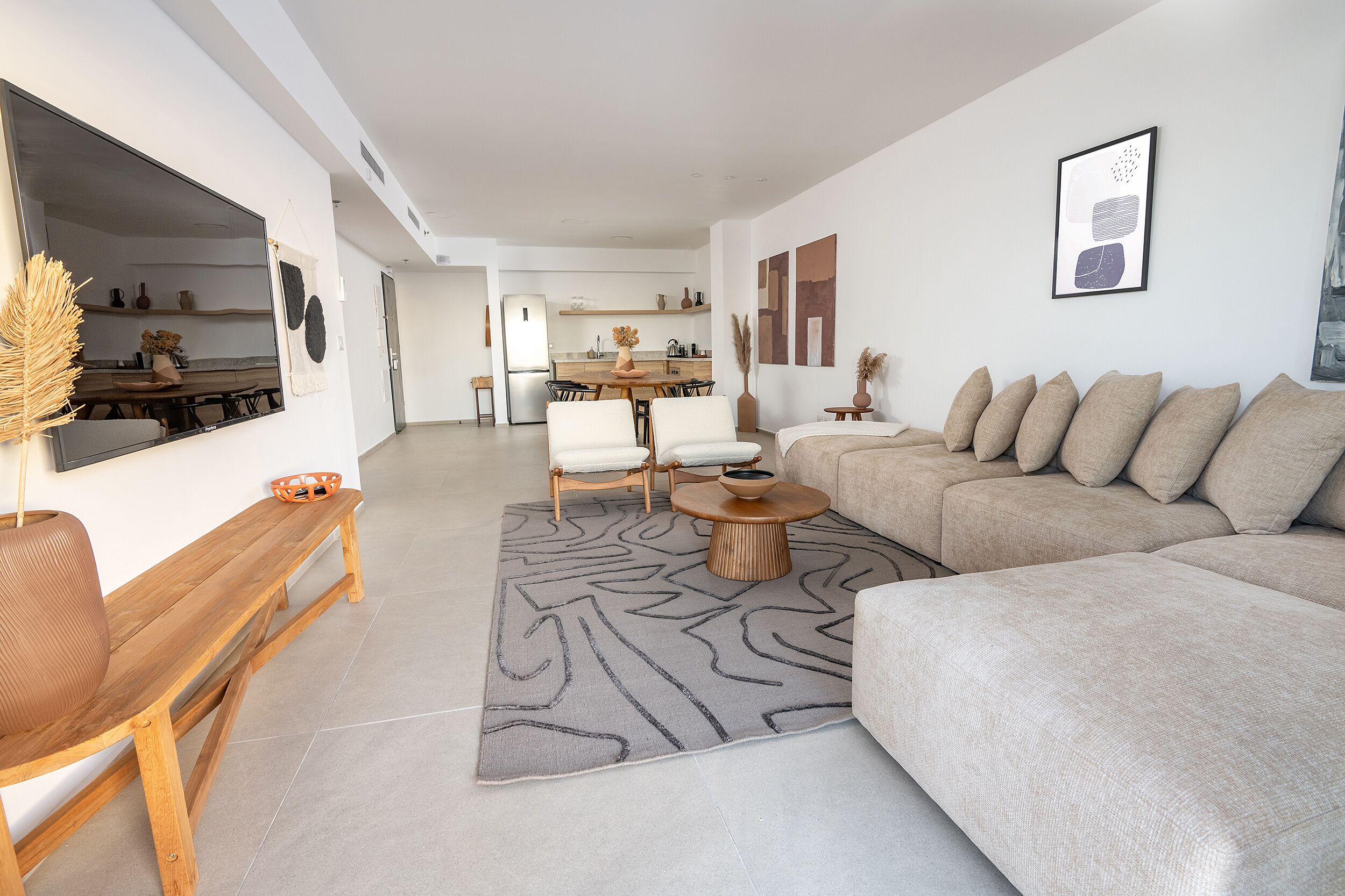 Een moderne woonkamer met een bank, een salontafel en een eethoek met stoelen en een tafel.
