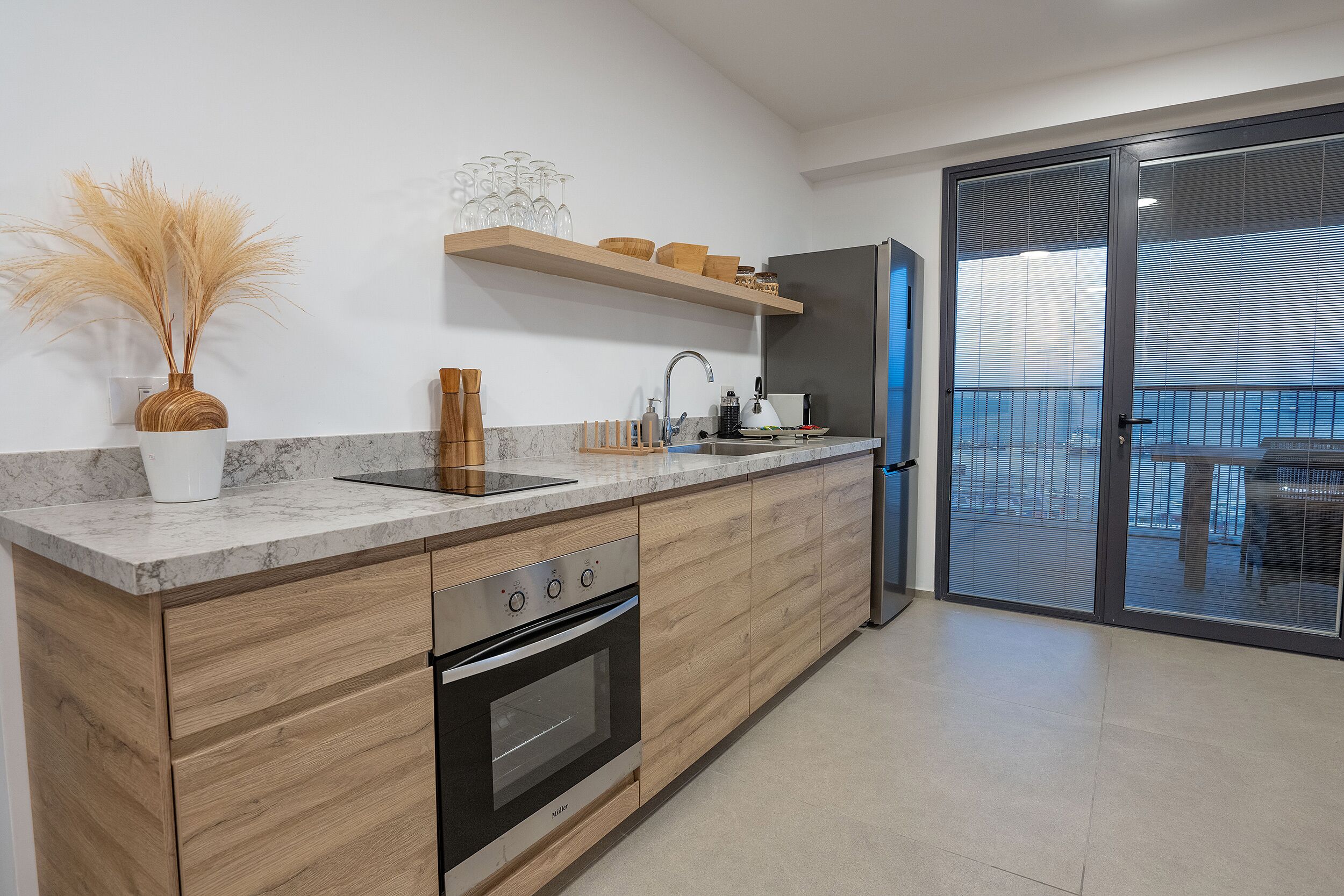 A modern kitchen with wooden cabinets, a built-in oven, and a stainless steel refrigerator.