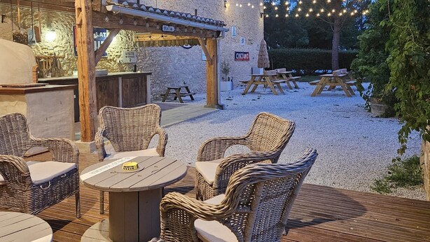 Un patio al aire libre con muebles de mimbre y un muro de piedra.