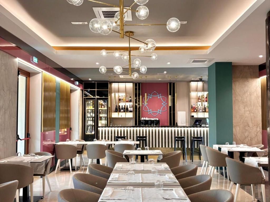 A modern restaurant interior with a bar area, seating arrangements, and a decorative ceiling light fixture.
