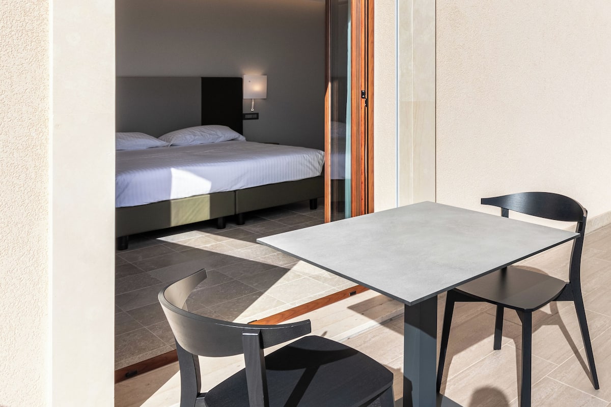 Un balcón con una cama y una mesa con sillas.