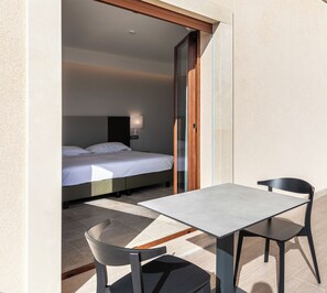 A balcony with a bed and a table with chairs. - Hotel Netum Mare (Noto)