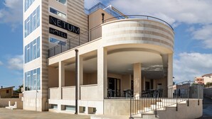 Un hotel moderno con un balcón curvo, varios pisos y un amplio espacio exterior con asientos.