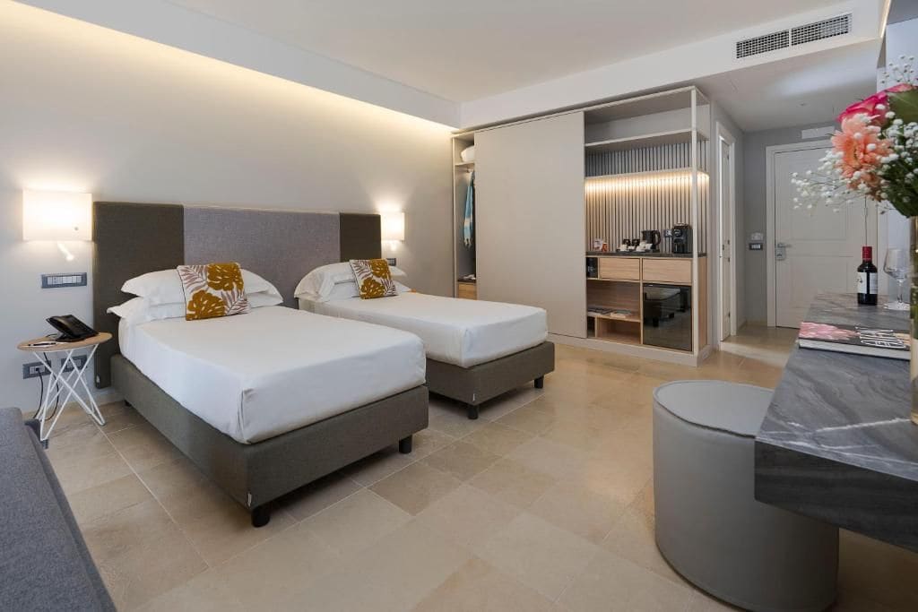 A hotel room with two beds, a desk, a chair, a wardrobe, and a bathroom.