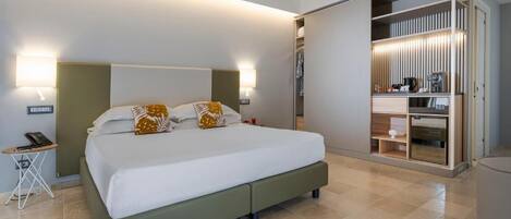 Una habitación de hotel moderna con una cama grande, lámparas de noche, una mesita y un vestidor.