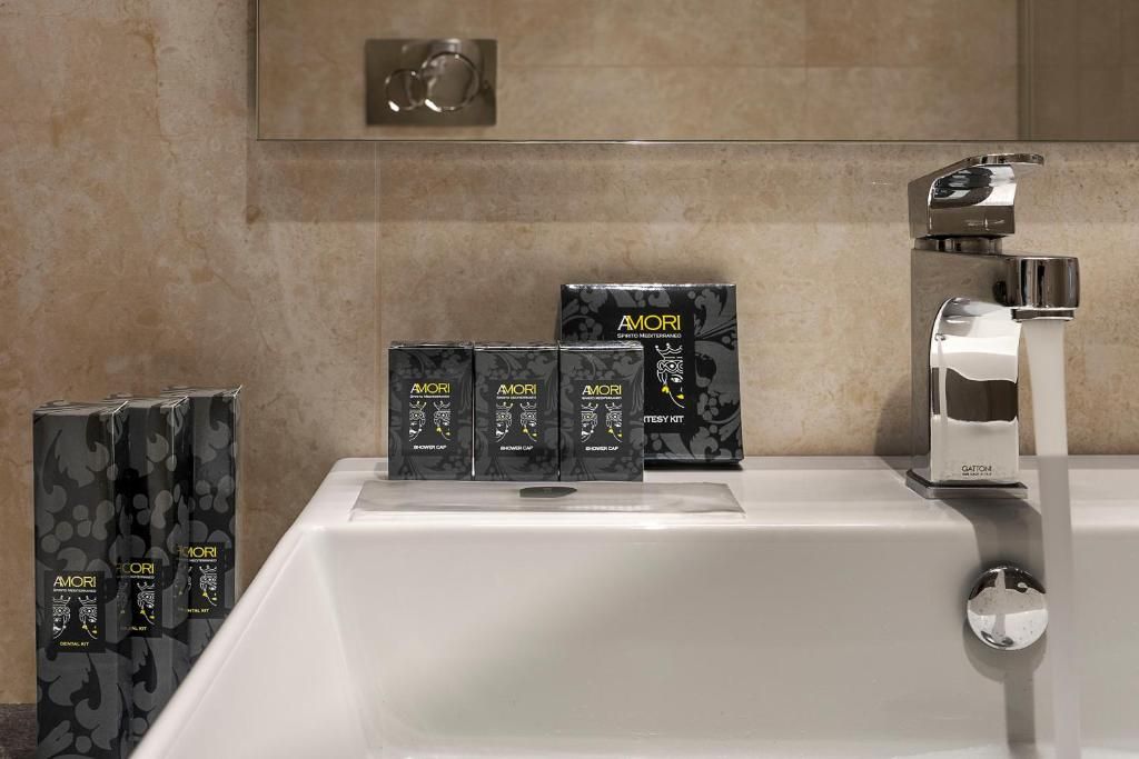 A bathroom with a white bathtub, a chrome faucet, and three boxes of AMORI shaving cream.