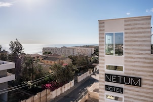 Un moderno edificio de hotel con un letrero que dice "NETUM HOTEL" y vista al mar.