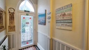 A hallway with a clock, a stained glass door, and a wall with motivational signs. - Rowcroft Lodge  (Paignton)