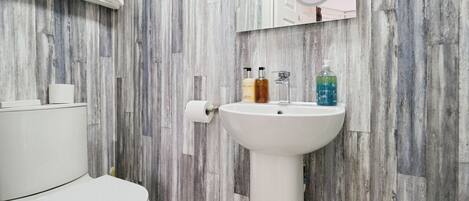 Ein Badezimmer mit Toilette und Waschbecken in Weiß sowie einem Spiegel über dem Waschbecken.