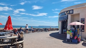 A seaside café with outdoor seating and a visible menu board. - Rowcroft Lodge  (Paignton)