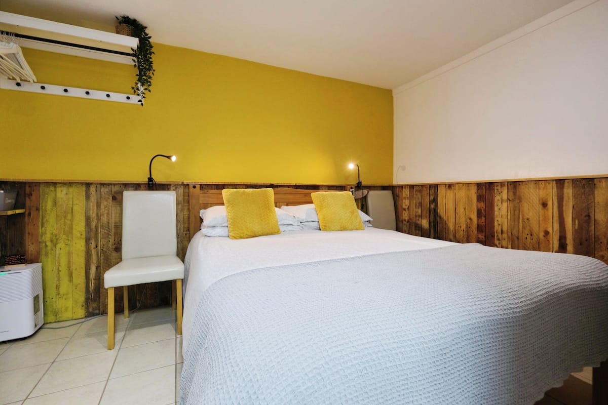 A room with a bed, a chair, and a wooden wall.