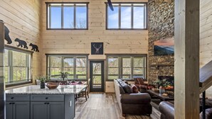 A spacious kitchen with a large island, wooden walls, and a stone fireplace.