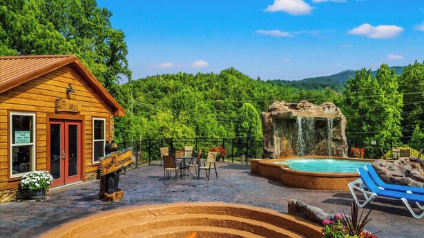 Una cabaña de madera con puerta roja, jacuzzi y una cascada.