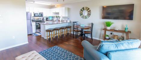 A modern kitchen with white cabinets, a microwave, and a large island with bar stools.