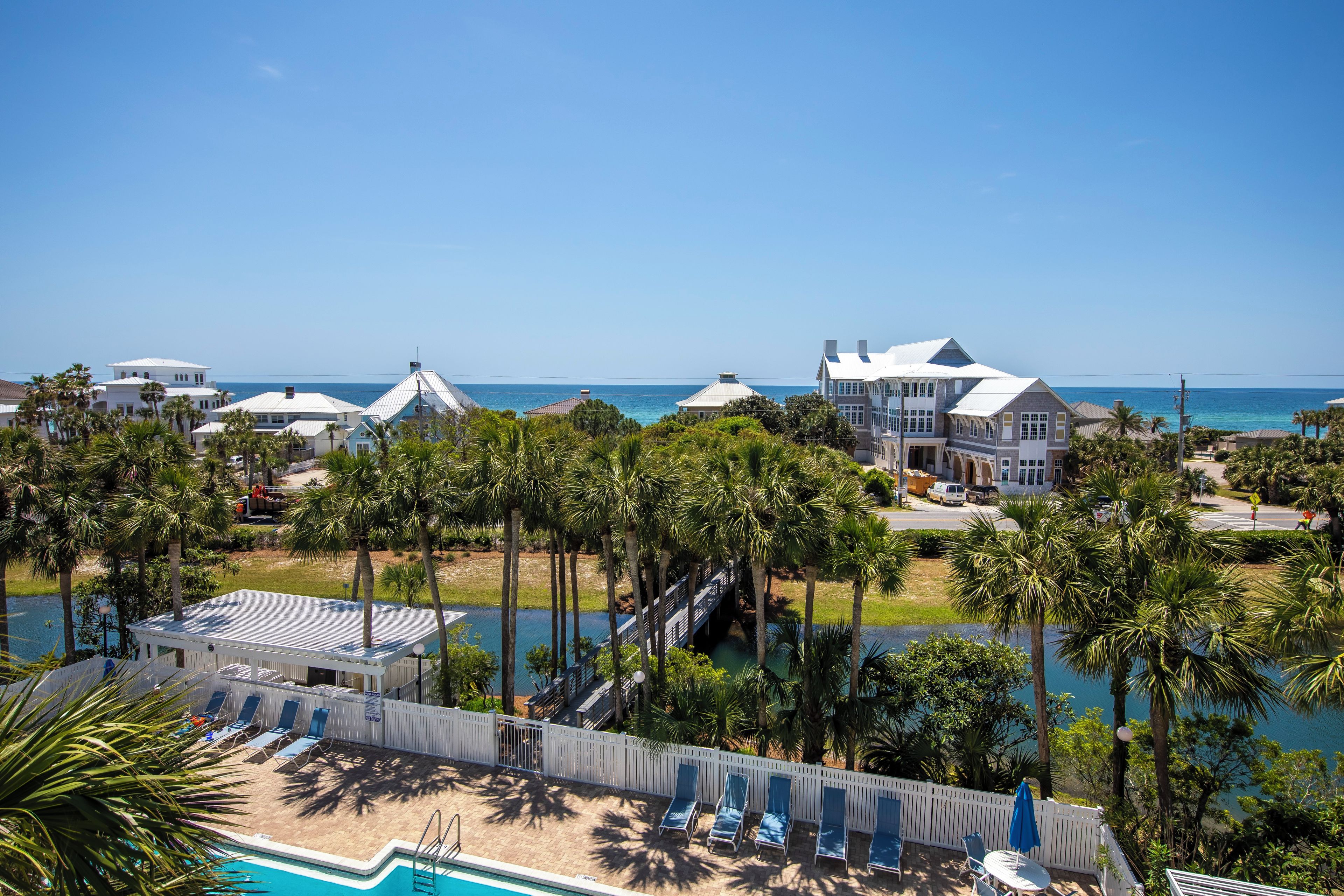 A coastal resort with multiple buildings, a swimming pool, and palm trees.