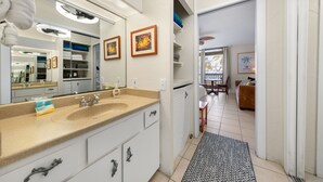 Ett modernt badrum med en stor spegel, en beige bänkskiva och en rymlig klädkammare.