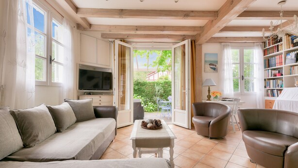 Un salon confortable avec un canapé, des fauteuils, un téléviseur et une bibliothèque.