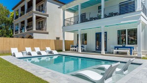 A modern two-story house with a swimming pool, outdoor seating, and a covered patio.