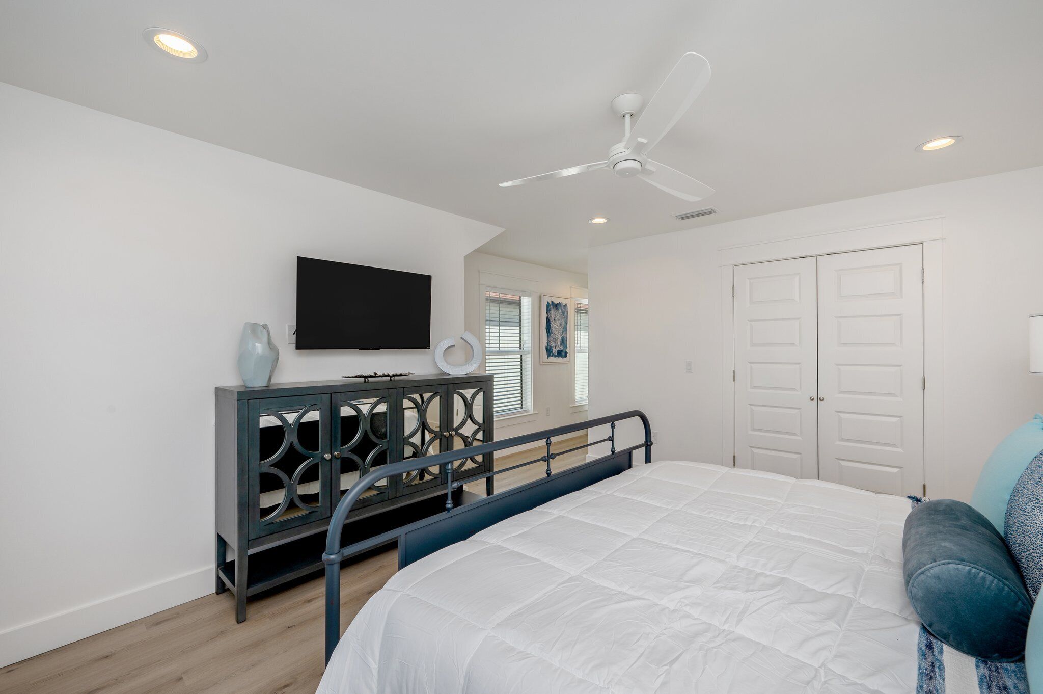 A bedroom with a bed, a dresser, a television, and a ceiling fan.