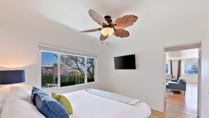 A bedroom with a bed, pillows, a ceiling fan, a TV, and a view of the outside. - Ocean Front Across From Beach/Amazing Views (La Jolla)