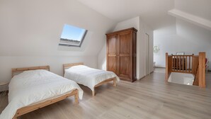 Un dormitorio con dos camas de madera, un armario grande y un tragaluz.