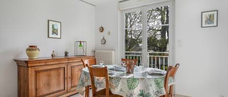 A dining area with a wooden cabinet, a table with chairs, and a window with a view of trees.