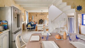 Une cuisine moderne avec un coin repas, des murs en pierre et une vue sur le salon.