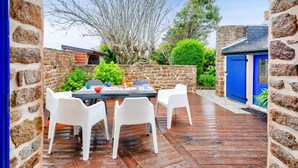 Une terrasse avec un mur en pierre, une porte bleue et une table entourée de chaises.