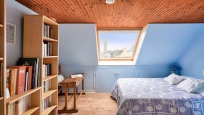 A bedroom with a sloped ceiling, wooden bookshelves, a bed with patterned bedding, and a skylight. - 250m from the beach, house for 6, Île Tudy (Ile Tudy)